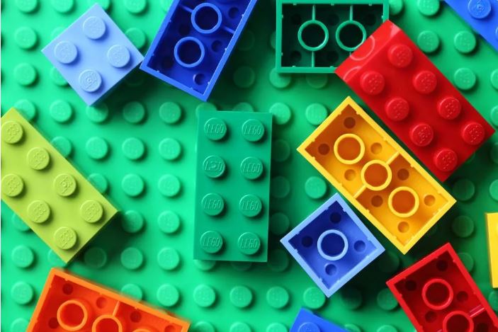 Colorful LEGO bricks scattered on a green base plate