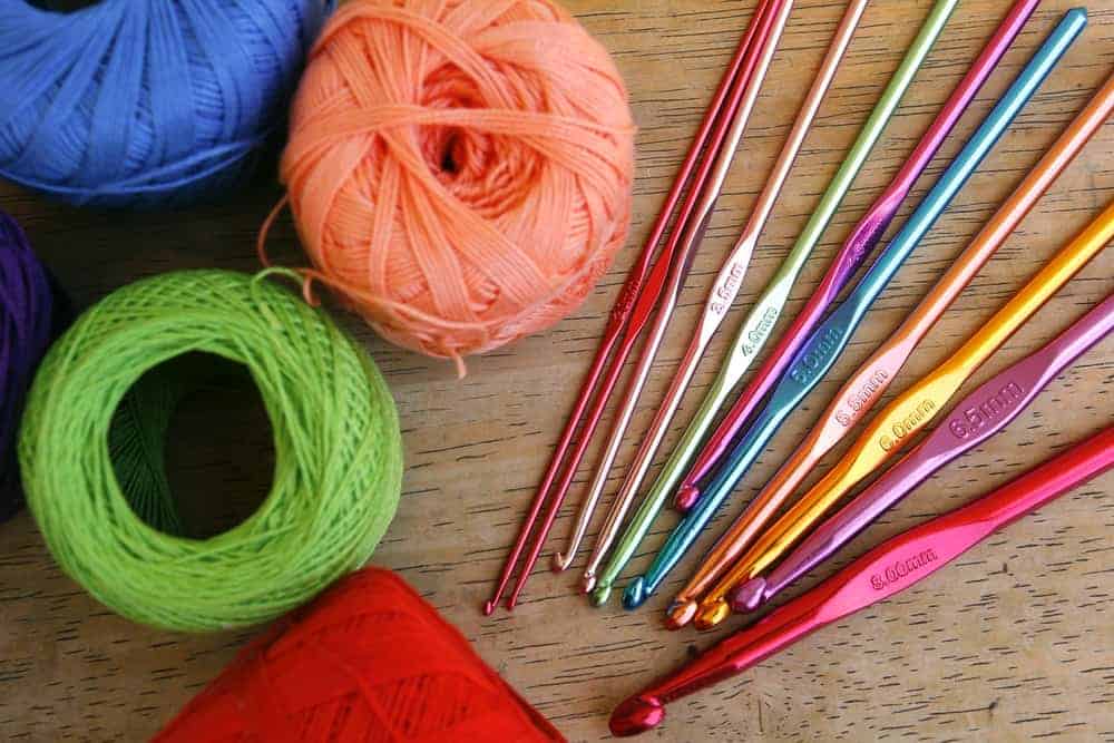 Balls of colorful yarn and several colorful crochet hooks in various sizes