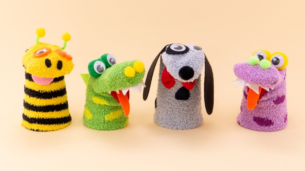 Four sock puppets: a giraffe, a green monster, a dog, and a purple monster