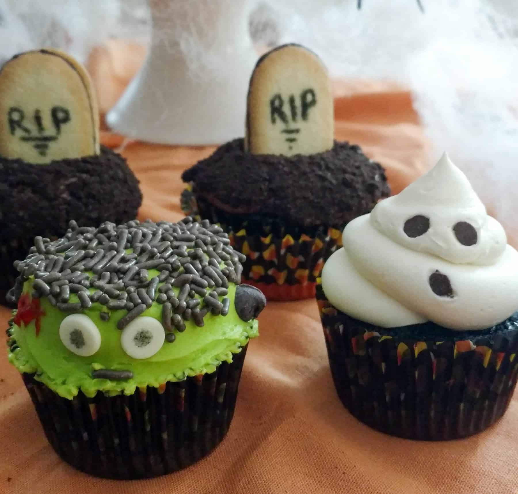 Cupcakes decorated for Halloween. One looks like Frankenstein and another looks like a ghost