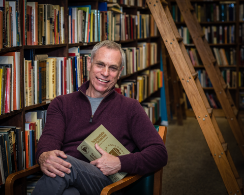 Storyteller Dave Matlack sits in a chair in a library.