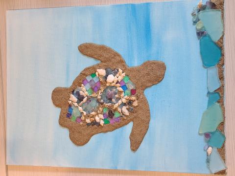 Blue background with a turtle silhouette; small shells, beads, and glass chips on the shell. 