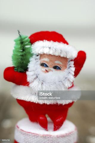 A pipe cleaner santa claus holding a small pine tree