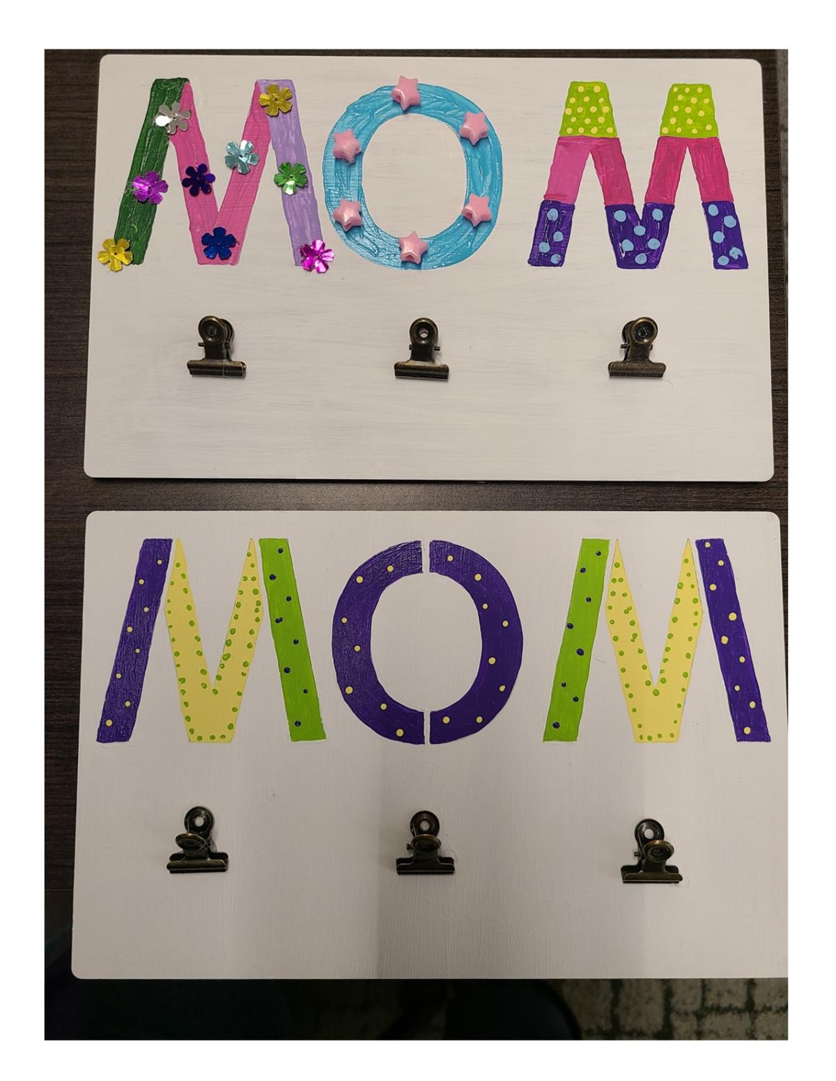 Two wooden plaque with "mom" painted in various colors and three metal clips